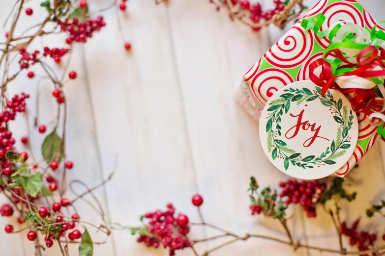 a close up of a wreath with a gift on it, inspired by Joy Garnett, pexels, graffiti, background image, on a white table, green bright red, label