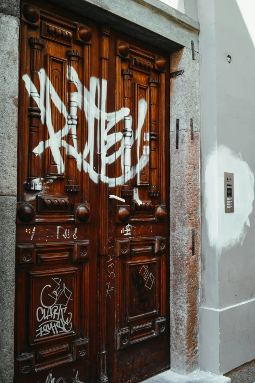 a wooden door sitting on the side of a building, by Muqi, pexels contest winner, graffiti, antoni tapies and cy twombly, white marble buildings, thumbnail, riot