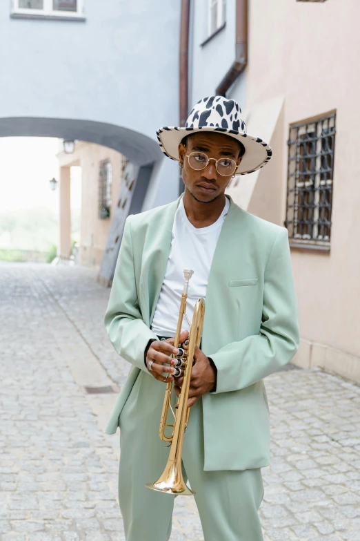 a man in a green suit and hat holding a trumpet, an album cover, inspired by Barthélemy Menn, pexels contest winner, antipodeans, delicate androgynous prince, street wear, square, raden saleh