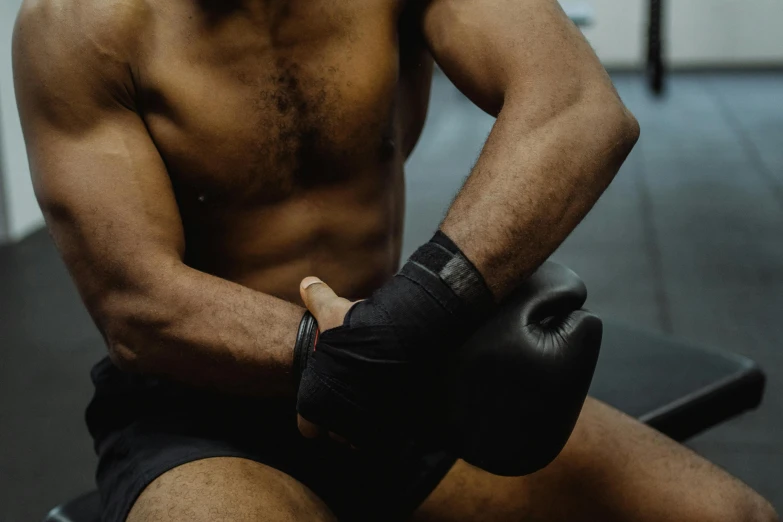 a man sitting on a bench wearing boxing gloves, profile image, ripped flesh, local gym, black man