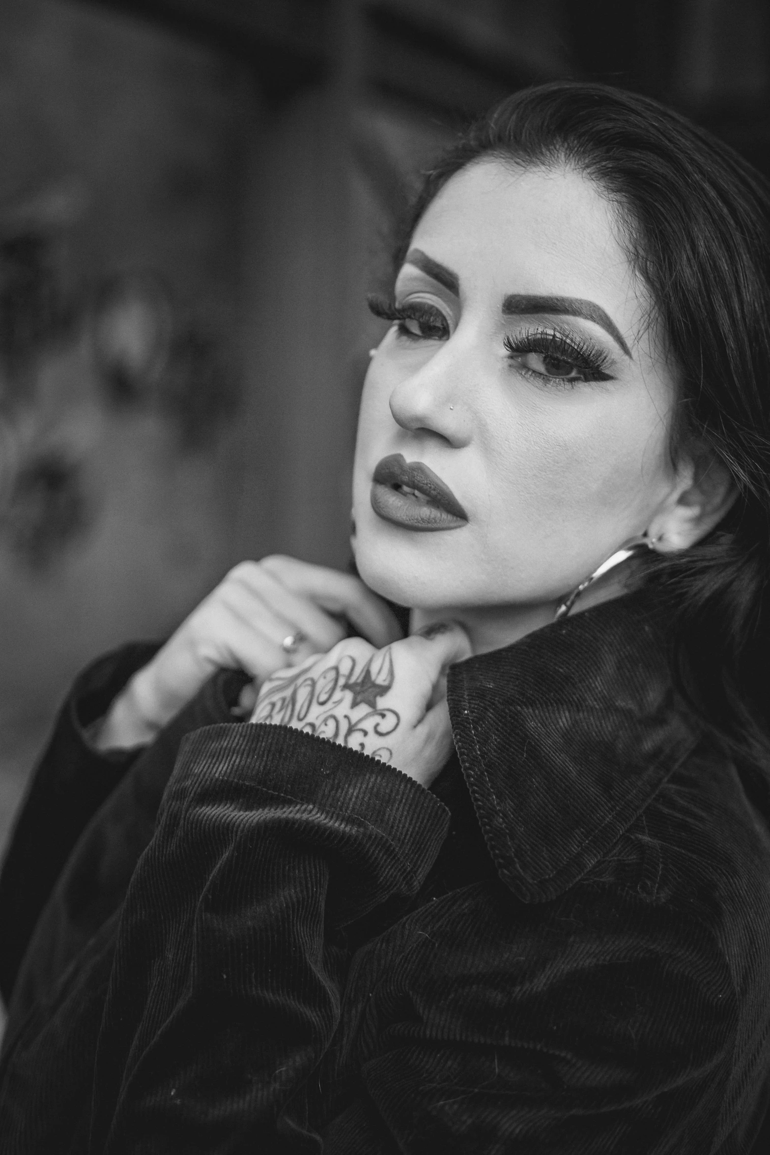 a woman with a tattoo on her arm, a black and white photo, inspired by Lucia Peka, trending on pexels, lowbrow, young middle eastern woman, she wears a jacket, thick lips, lowres