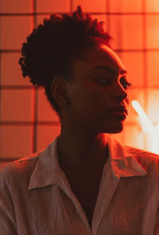 a woman standing in front of a red light, inspired by Nan Goldin, pexels contest winner, visual art, african american young woman, studio backlight, pensive, androgynous male