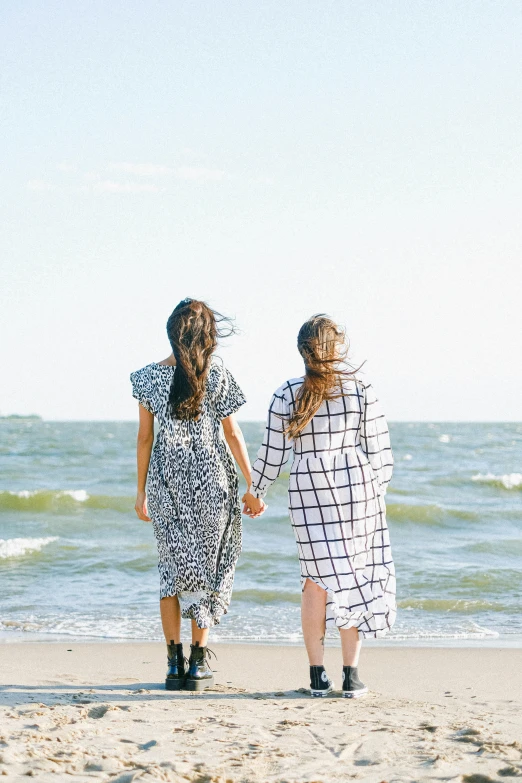 two women walking on the beach holding hands, unsplash, happening, patterned clothing, infp young woman, wearing a simple robe, teenage girl