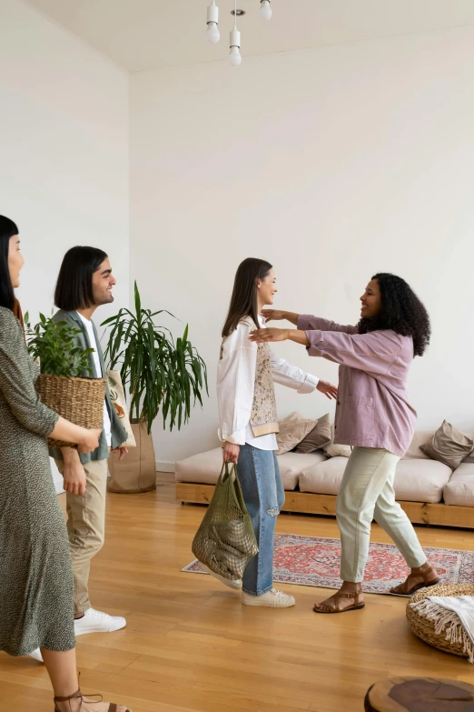 a group of people standing in a living room, reaching out to each other, dressed with long fluent clothes, gifts, wearing a linen shirt