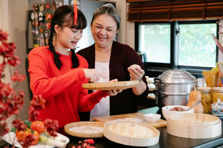 two women standing in a kitchen preparing food, inspired by Cui Bai, pexels contest winner, mingei, avatar image, family dinner, slightly round chin, gourmet and crafts