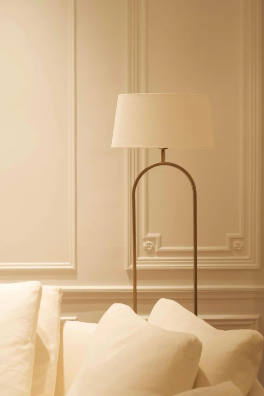a white couch sitting in a living room next to a lamp, inspired by Évariste Vital Luminais, tonalism, white sweeping arches, close up angle, paris hotel style, tall thin frame