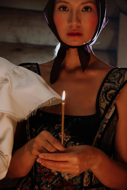 a woman holding a lit candle in her hands, an album cover, inspired by Pietro Longhi, trending on pexels, renaissance, seductive gaze, scene from church, blindfold, historically accurate