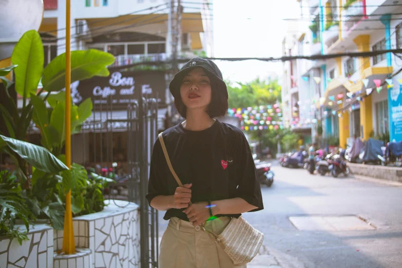 a woman standing in the middle of a street, by Tan Ting-pho, black t shirt, ulzzang, baggy clothing and hat, small heart - shaped face