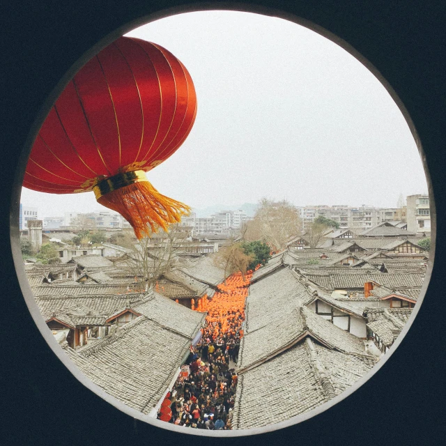 a view of a city through a round window, an album cover, inspired by Gu An, chinese lanterns, unsplash photo contest winner, people watching, above a village