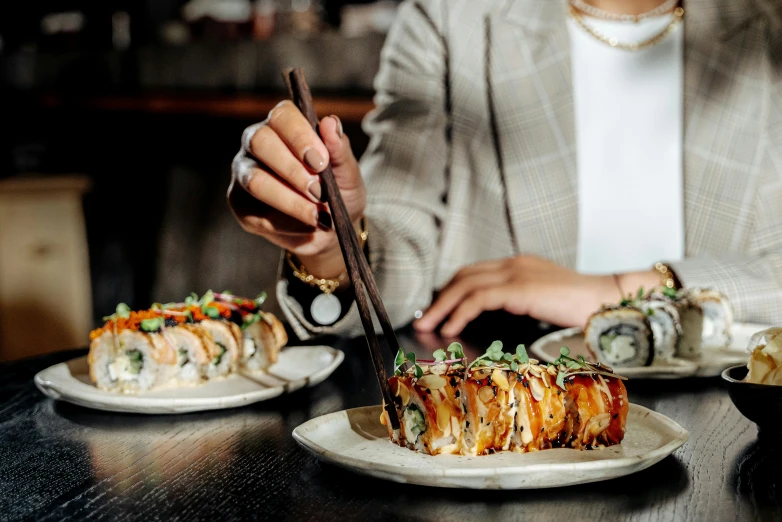 a woman eating sushi with chopsticks at a restaurant, by Julia Pishtar, unsplash, multiple stories, te pae, katana in hand, foil