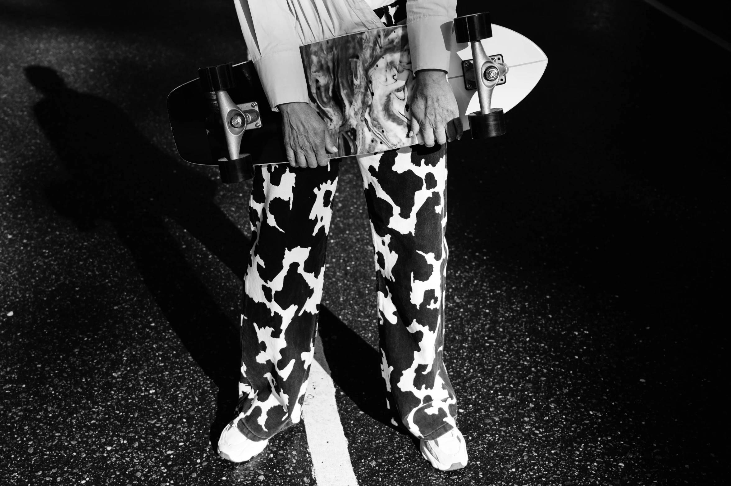 a black and white photo of a person holding a skateboard, a black and white photo, by Maurycy Gottlieb, cow, pants, 2020, photo from vogue magazine