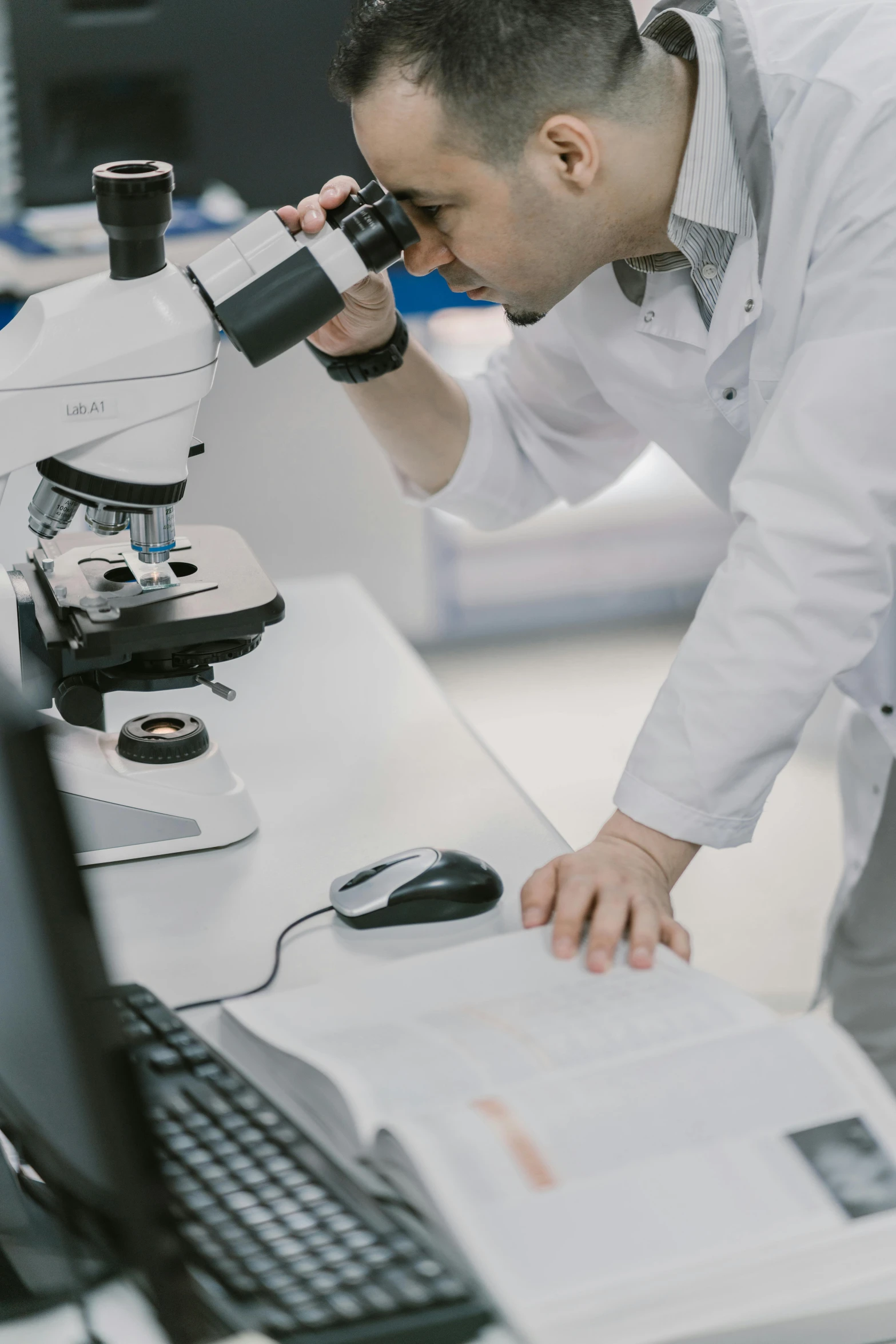 a man in a lab looking through a microscope, pexels, low quality photo, ilustration, slightly pixelated, medical labels