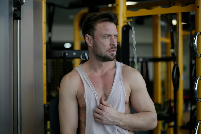 a man standing in front of a machine in a gym, a portrait, by Adam Marczyński, pexels contest winner, muscular! white, sweaty skin, music video, background image