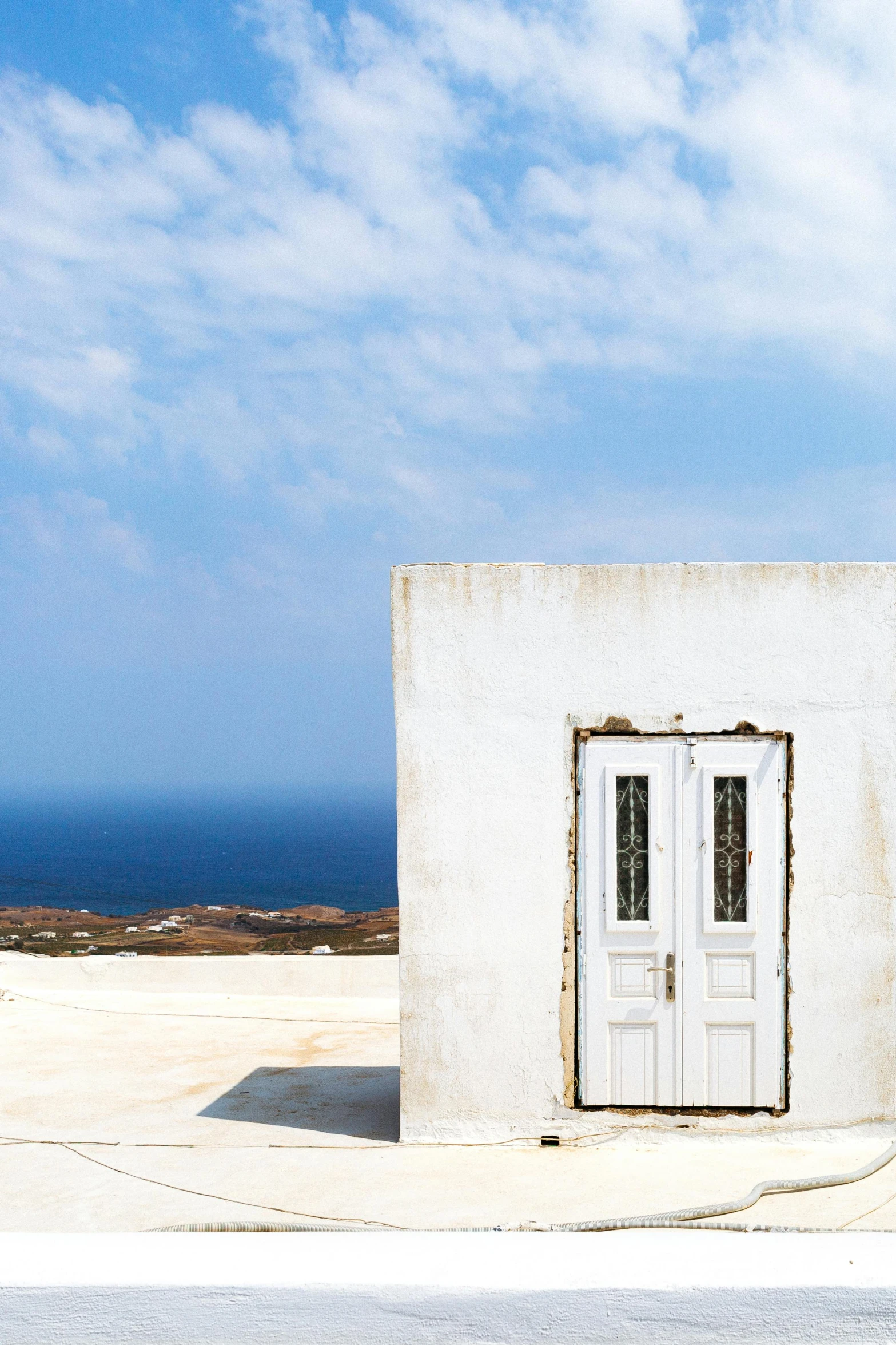 a red fire hydrant sitting in front of a white building, an album cover, pexels contest winner, minimalism, greek fantasy panorama, views to the ocean, wood door, desert white greenhouse