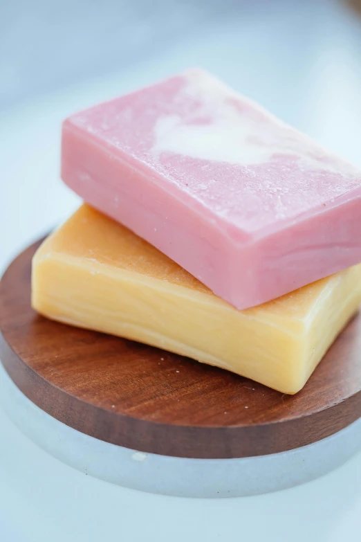 three soap bars stacked on top of each other, by Jessie Algie, on a wooden tray, pink and yellow, pristine and clean, juice