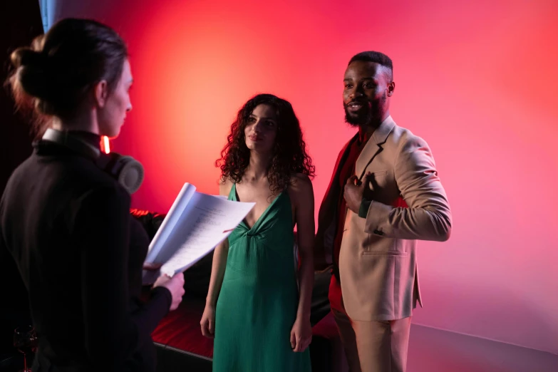 a man standing next to a woman in a green dress, pexels contest winner, red and cinematic lighting, behind the scenes photo, 3 actors on stage, charli bowater and artgeem