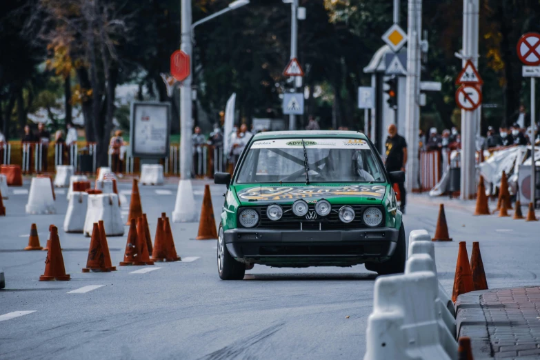 a green car driving down a street next to traffic cones, by Carlo Martini, pexels contest winner, renaissance, japanese drift car, vintage race footage, bangkok, square