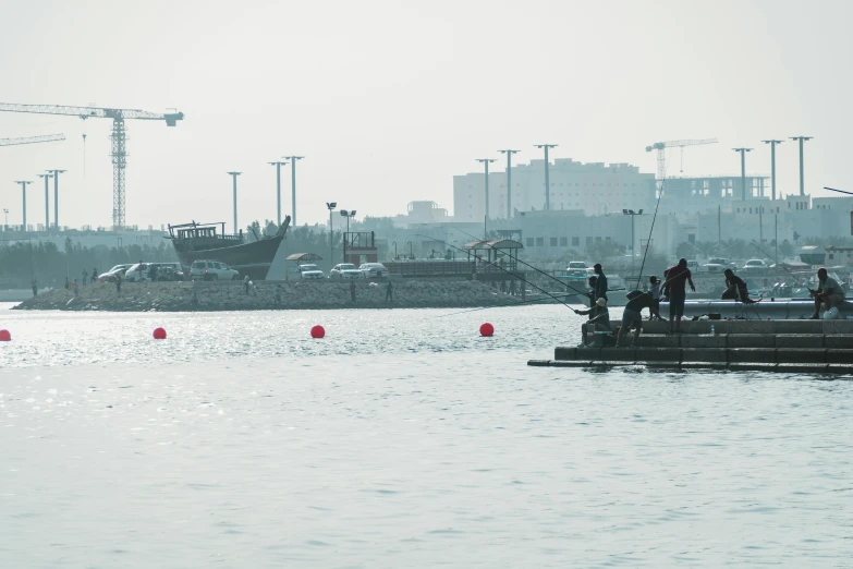 a group of people standing on a dock next to a body of water, hurufiyya, floating power cables, hazy, 2022 photograph, f 1