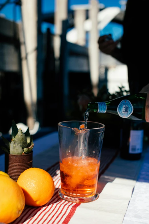 a person pouring a drink from a bottle into a glass, pexels contest winner, renaissance, al fresco, tilt and orange, slide show, at the terrace