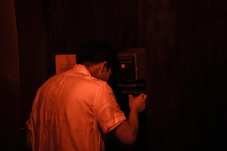 a man standing in front of a microwave in a dark room, inspired by Nan Goldin, private press, xiang duan, pacing in server room, red light, 33mm photo