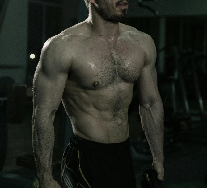 a shirtless man holding a kettlebell in a gym, a photo, by Adam Marczyński, holography, 30 year old man :: athletic, muscular werewolf, thick mustache, cable