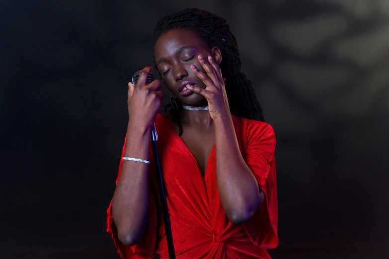 a woman in a red dress holding a microphone, by Winona Nelson, pexels contest winner, adut akech, eyes closed, red neon eyes, black young woman