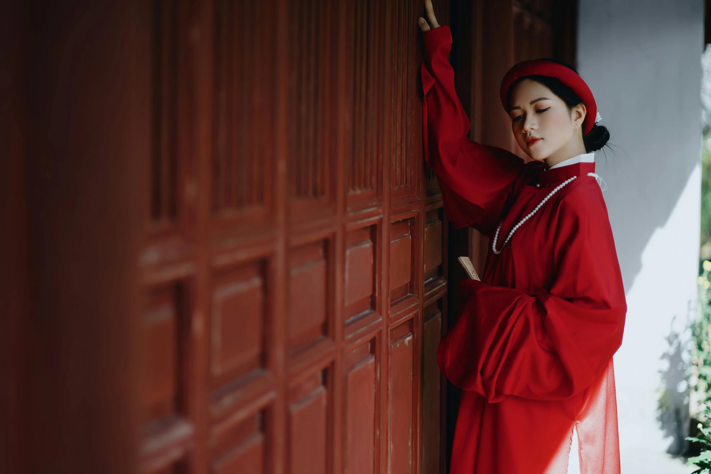 a woman in a red dress leaning against a wall, inspired by Gu An, pexels contest winner, wearing headmistress uniform, vietnamese temple scene, 15081959 21121991 01012000 4k, victorian style costume