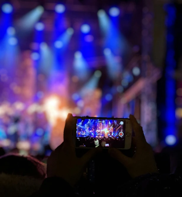 a person taking a picture of a concert, by Niko Henrichon, pexels, fantasy medium shot, holiday season, rectangle, unedited