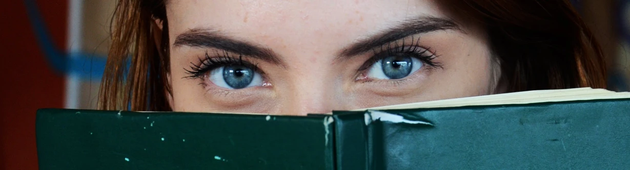 a close up of a person holding a book, sapphire blue eyes, large eyebrows, hunter eyes, beautiful eyes medium shot