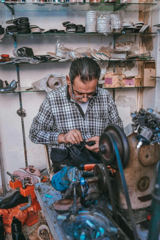 a man working on a sewing machine in a workshop, inspired by Afewerk Tekle, trending on pexels, arbeitsrat für kunst, real life photo of a syrian man, biker, made from mechanical parts, kurdish lawyer