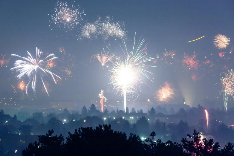 a bunch of fireworks that are in the sky, a photo, by Adam Marczyński, pexels contest winner, city buildings on top of trees, some mist grey smoke and fire, getty images proshot, taken on a 2010s camera