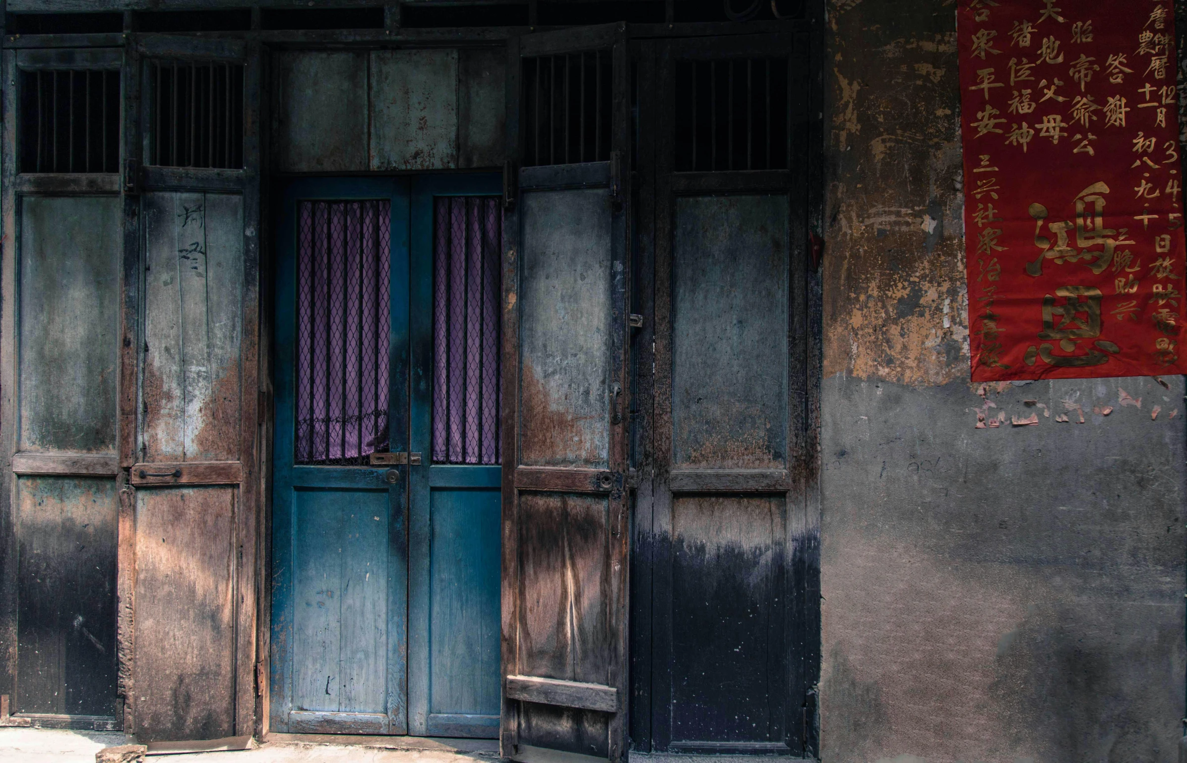 a dog laying on the ground in front of a building, by Jan Tengnagel, pexels contest winner, bengal school of art, blue colors with red accents, wood door, traditional chinese textures, buildings covered in black tar