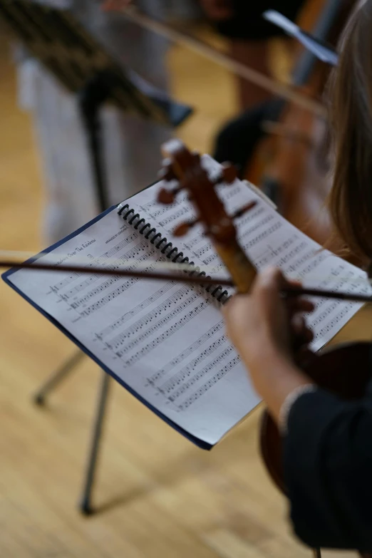 a close up of a person holding a violin, sheet music, subject in the centre, schools, thumbnail