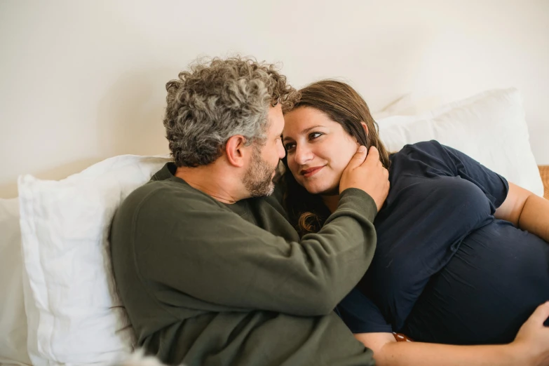 a man and a woman cuddling on a bed, pexels contest winner, anomalisa, third trimester, smiling at each other, coloured