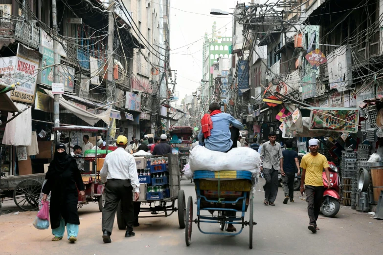 a man riding on the back of a cart down a street, dhaka traffic, people walking down a street, dezeen, getty images