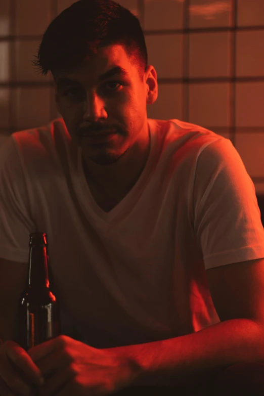 a man sitting at a table with a bottle of beer, inspired by Nan Goldin, pexels contest winner, renaissance, bisexual lighting, profile image, mid-shot of a hunky, riyahd cassiem