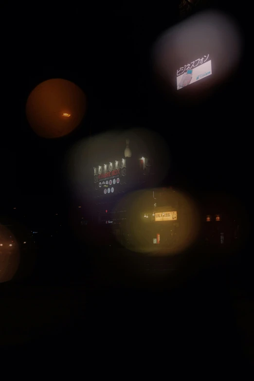 a blurry picture of a city at night, an album cover, reddit, drive in movie theater, chiaroscuro!!, orbs, low quality photo