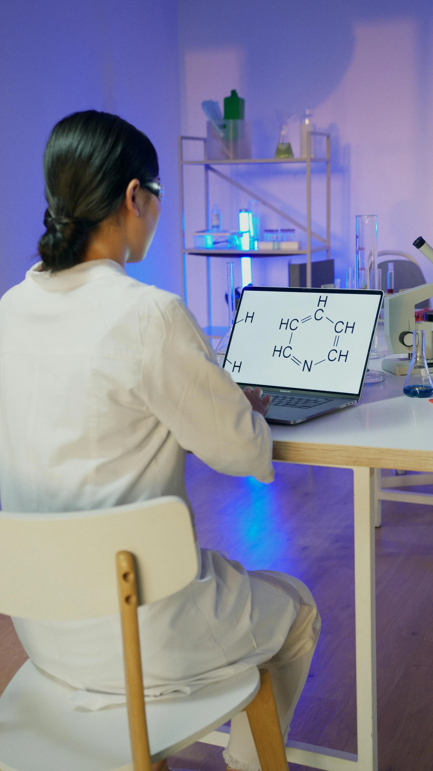 a woman sitting at a table in front of a laptop computer, analytical art, chemical woekshop, 15081959 21121991 01012000 4k, thumbnail, high quality photo