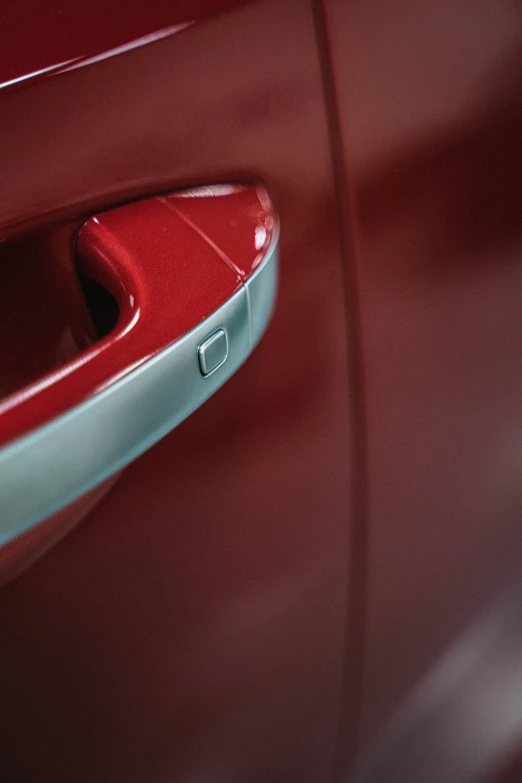 a close up of a red car door handle, pexels contest winner, photorealism, maroon metallic accents, high-body detail, 2 0 % pearlescent detailing, aerodynamic body