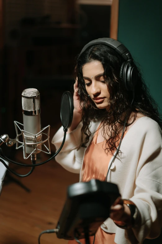 a woman sitting in front of a microphone in a recording studio, an album cover, trending on pexels, hurufiyya, maya ali, curls, movie photo, standing