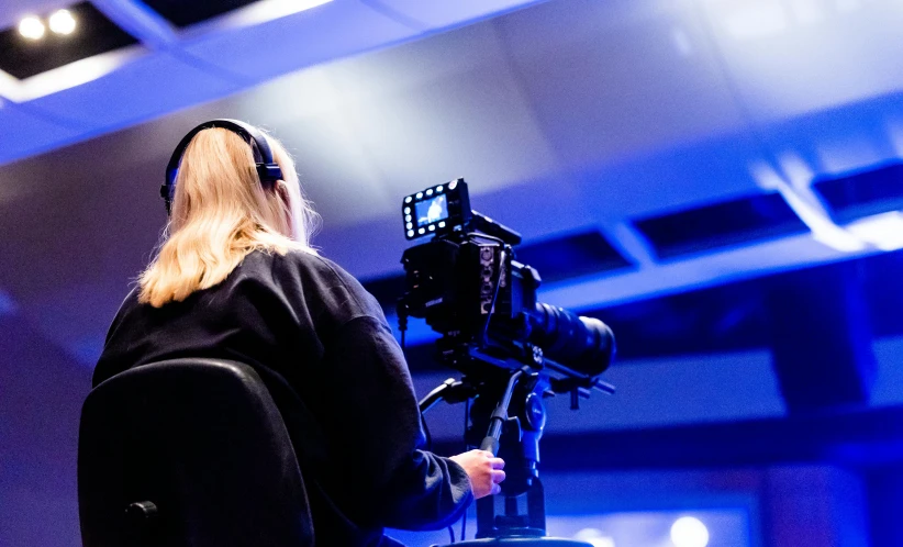 a woman that is standing in front of a camera, tv production, event photography, thumbnail, back to camera