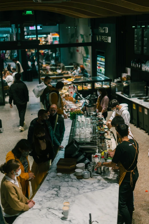 a group of people standing around a long table, food court, aussie baristas, dark and moody, inside a supermarket