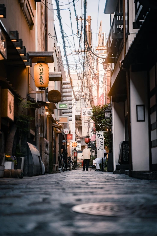 a couple of people walking down a street next to tall buildings, unsplash contest winner, ukiyo-e, cobblestone street, lots of light, ethnicity : japanese, quiet street
