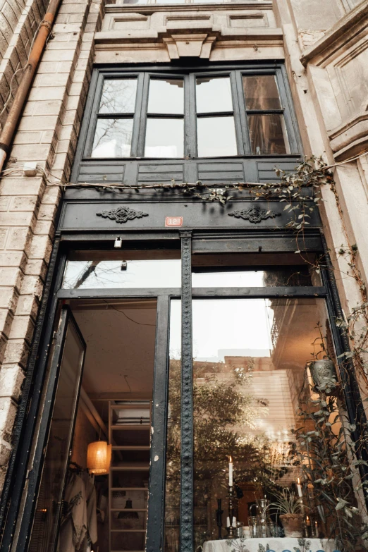 a very tall building with a bunch of windows, a photo, pexels contest winner, art nouveau, doorway, small hipster coffee shop, with black vines, thumbnail