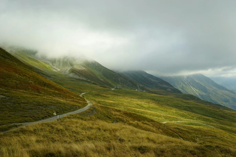 a winding road in the mountains on a cloudy day, by Werner Andermatt, pexels contest winner, les nabis, hunting, caspar friedrich, riding, ignant