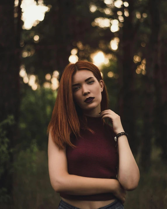 a woman standing in the middle of a forest, inspired by Elsa Bleda, trending on pexels, renaissance, red hair and attractive features, dark lipstick, non-binary, early evening