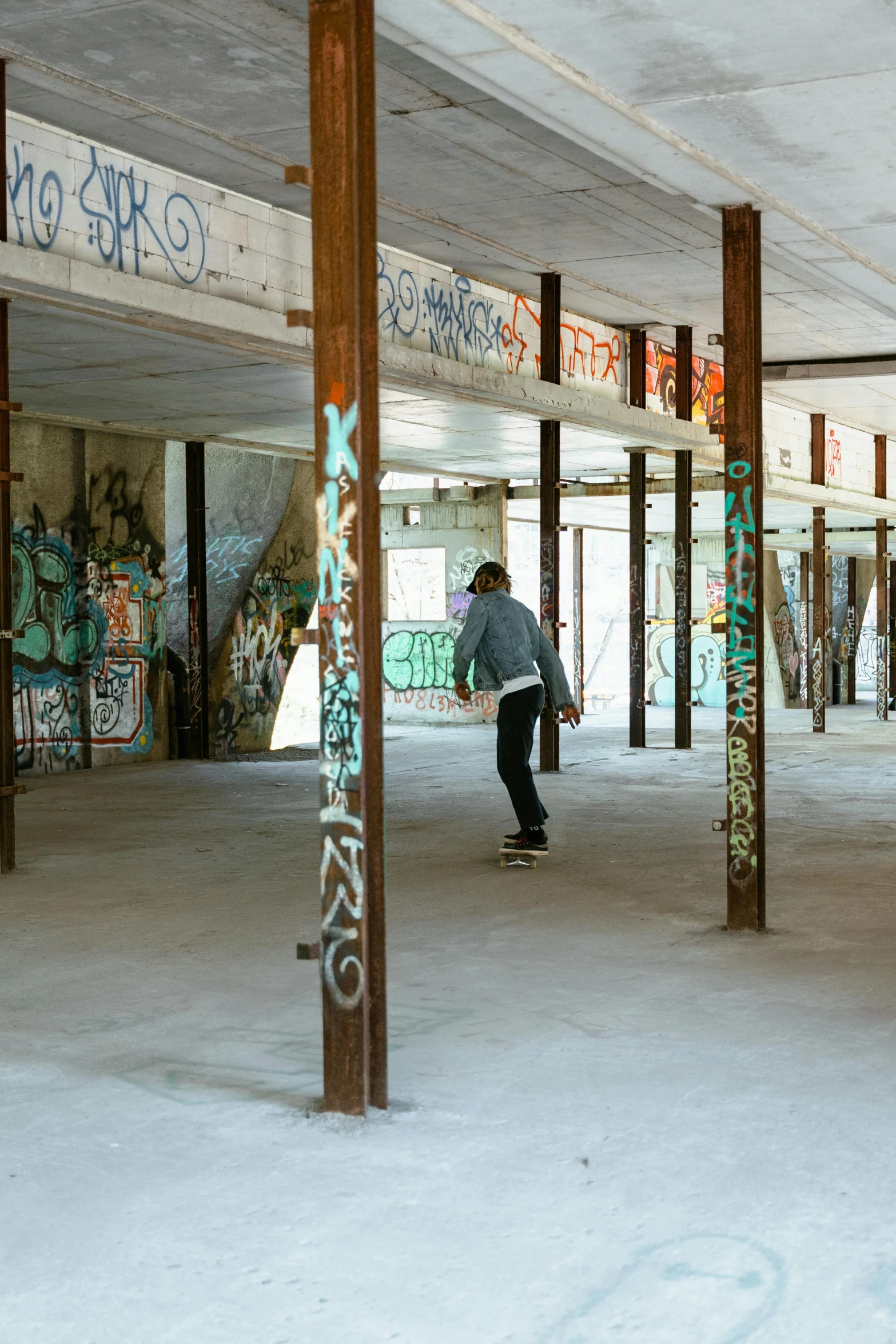 a man riding a skateboard inside of a building, graffiti, old lumber mill remains, concrete pillars, office/thrift store/social hall, six sided