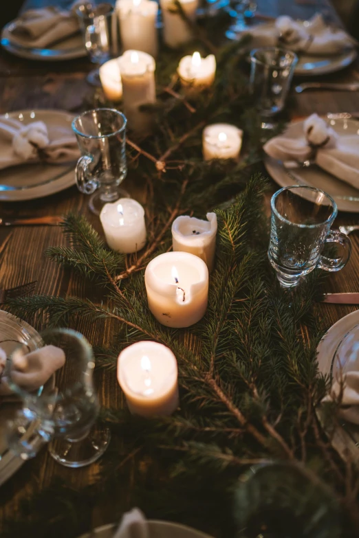 a table that has a bunch of candles on it, evergreen branches, uncropped, item, glassware