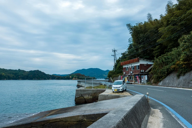 a car parked on the side of a road next to a body of water, inspired by Hasui Kawase, unsplash, shin hanga, small port village, thumbnail, tochigi prefecture, street view