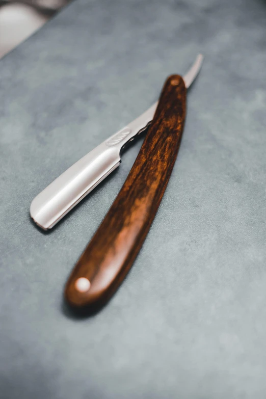 a pair of razors sitting on top of a table, ebony wood bow, holds a small knife in hand, thumbnail, dark brown